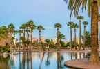 Office buildings in Phoenix, viewed from across the lagoon in Encanto Park, glow gold in the rays of the setting sun.