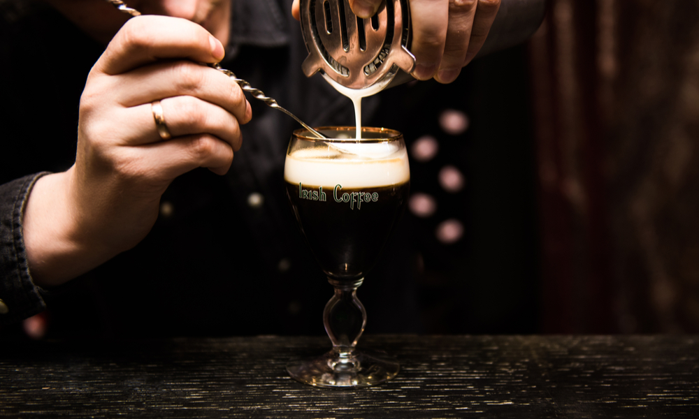 Irish Coffee cups with cream on a dark background, on the bar, warming cocktail, cooking process