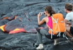 Tourists taking photo of flowing lava from Kilauea volcano around Hawaii volcanoes national park, USA.