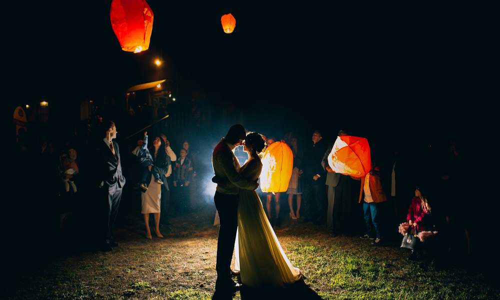 newly married couple embracing each other with the red Chinese sky lanterns in the background.