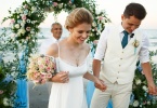 Happy newlyweds walk from wedding altar on the sea shore