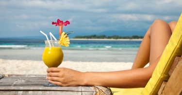 woman enjoying a cocktail on a caribbean beach