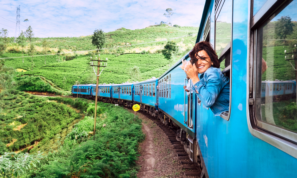 Happy smiling woman looks out from window traveling by train