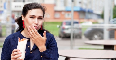 Beautiful girl with an appetite eating a burrito on the street