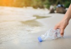 Hand woman picking up plastic bottle cleaning on the beach