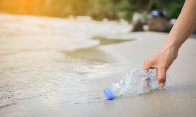 Hand woman picking up plastic bottle cleaning on the beach