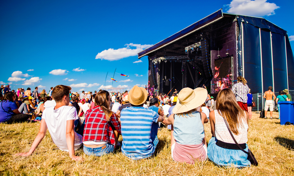 Teenagers, summer music festival, sitting in front of stage