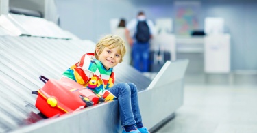 child sitting on baggage conveyor belt