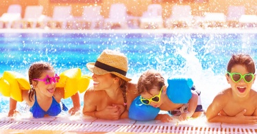 Happy family in the pool, having fun in the water, mother with three kids enjoying aqua park