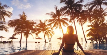 Woman enjoying vacation holidays at luxurious beachfront hotel resort with swimming pool and tropical lansdcape near the beach