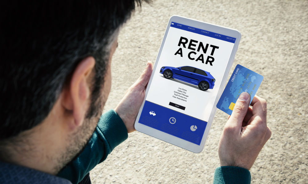 man holding a tablet renting a car and a credit card