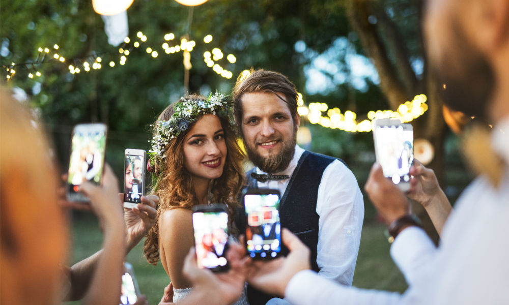 guests at wedding using phones to snap bride and groom