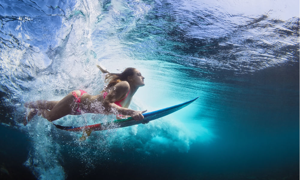 urfer with surf board dive underwater with fun under big ocean wave. 