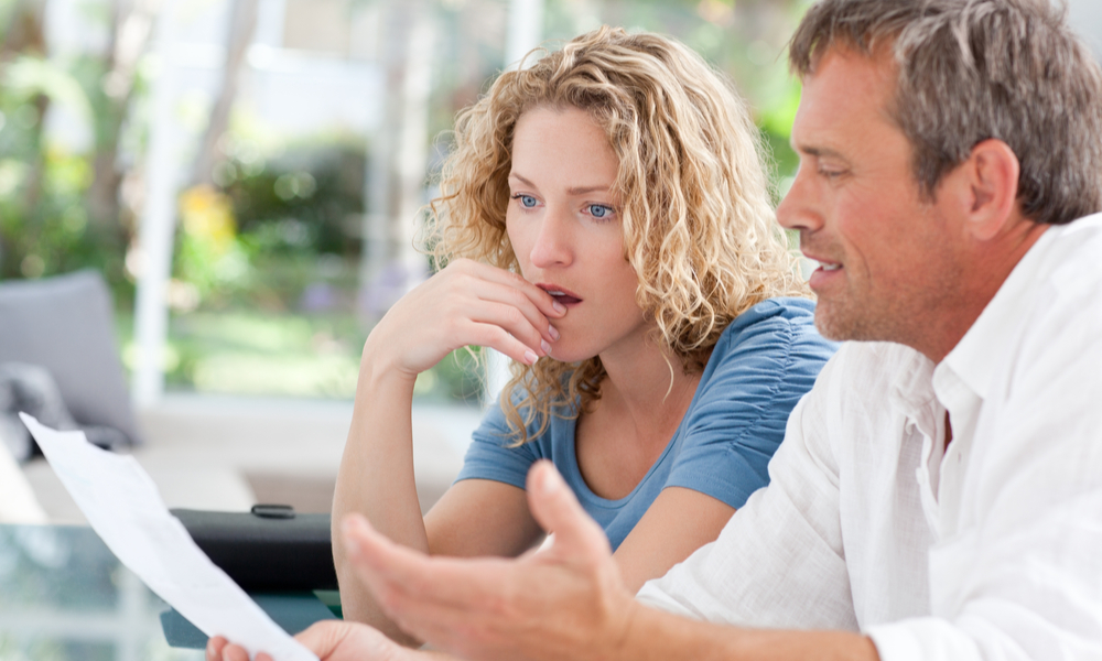 man and woman looking at a paper with anger