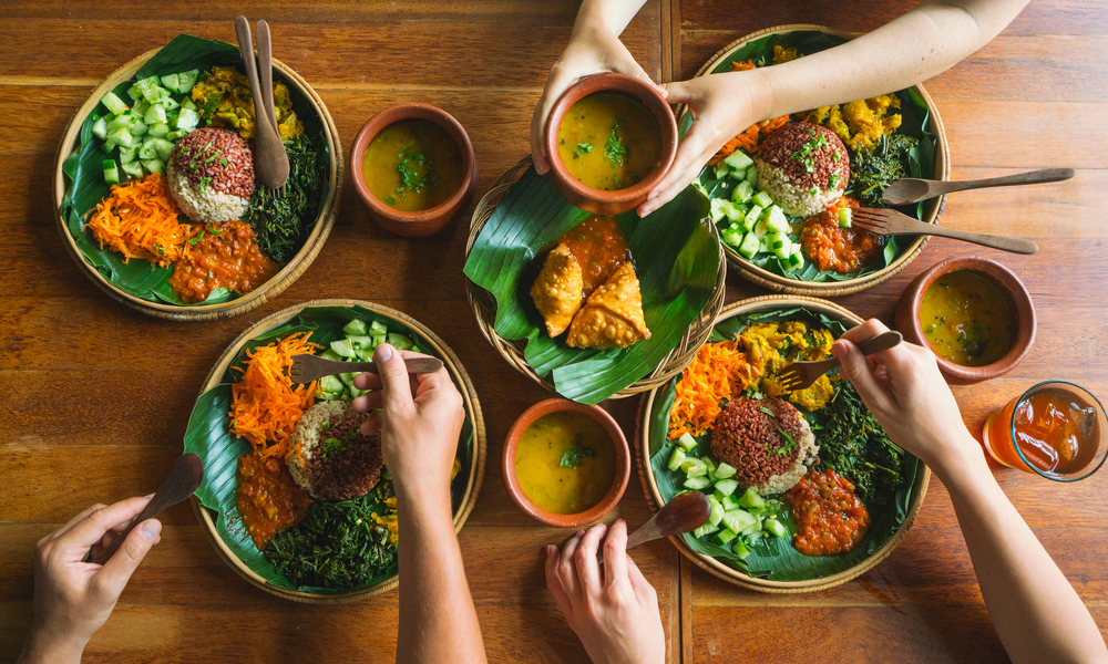 several people eat Indian food at a common table together