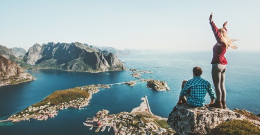 Couple travelers traveling together on top cliff Reinebringen mountain in Norway