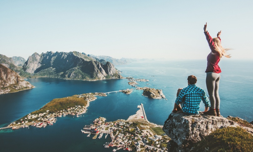 Couple travelers traveling together on top cliff Reinebringen mountain in Norway