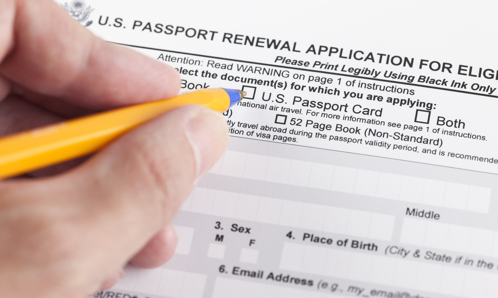 U.S. passport renewal application for eligible individuals and human hand with ballpoint pen