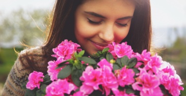 young woman smelling pink flowers