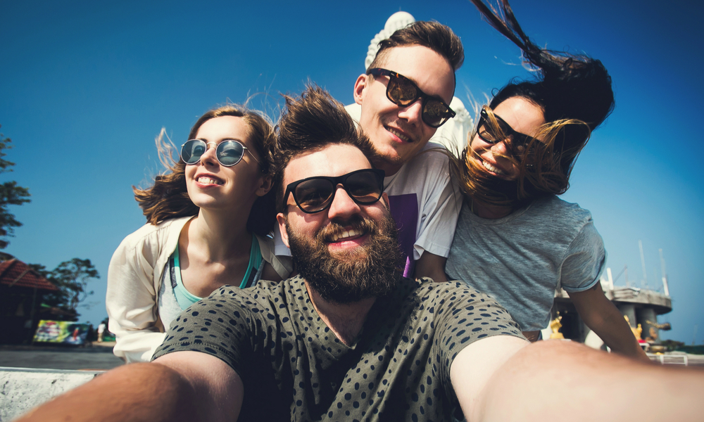 Multiracial group of young hipster friends make selfie photo with smartphone camera in Phuket while traveling across Thailand on vacation.