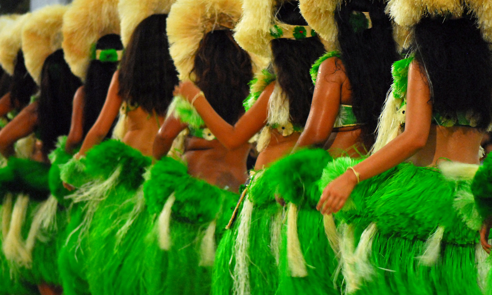 Group of Polynesian dancers in traditional green dresses performing