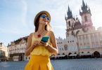 Young woman in yellow walking with smart phone on the old town square in Prague city