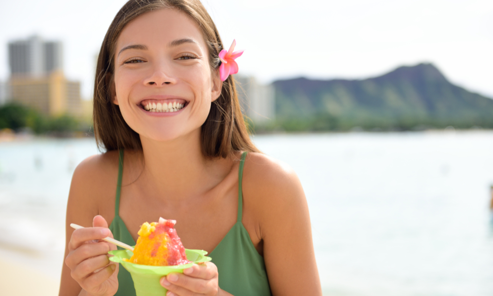 Hawaii woman on beach eating Hawaiian shave ice, a local shaved ice dessert