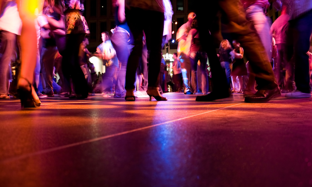 A low shot of the dance floor with people dancing under the colorful lights