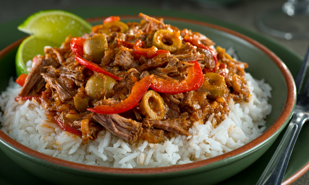 A delicious cuban ropa vieja stew on a bed of rice with lime garnish