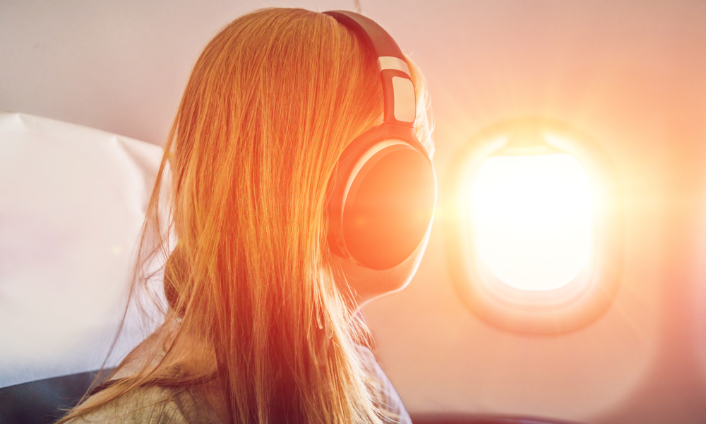 Girl Staring Out Plane Widow With Headphones