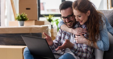 young couple on their laptop are jubilant on finding cheap flights for Black Friday