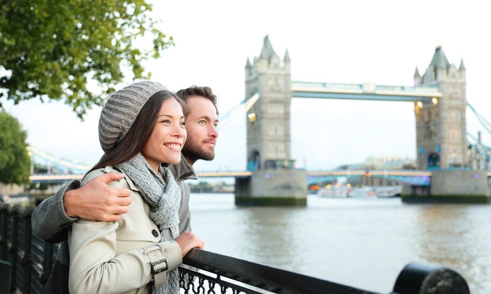 Mistakes to Avoid When Looking for Cyber Monday Flight Deals: young couple looking over London tower bridge in the UK