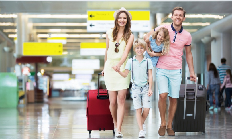 7 Thanksgiving Travel Tips to Make Your Holiday Stress-Free: Happy family with suitcases in the airport