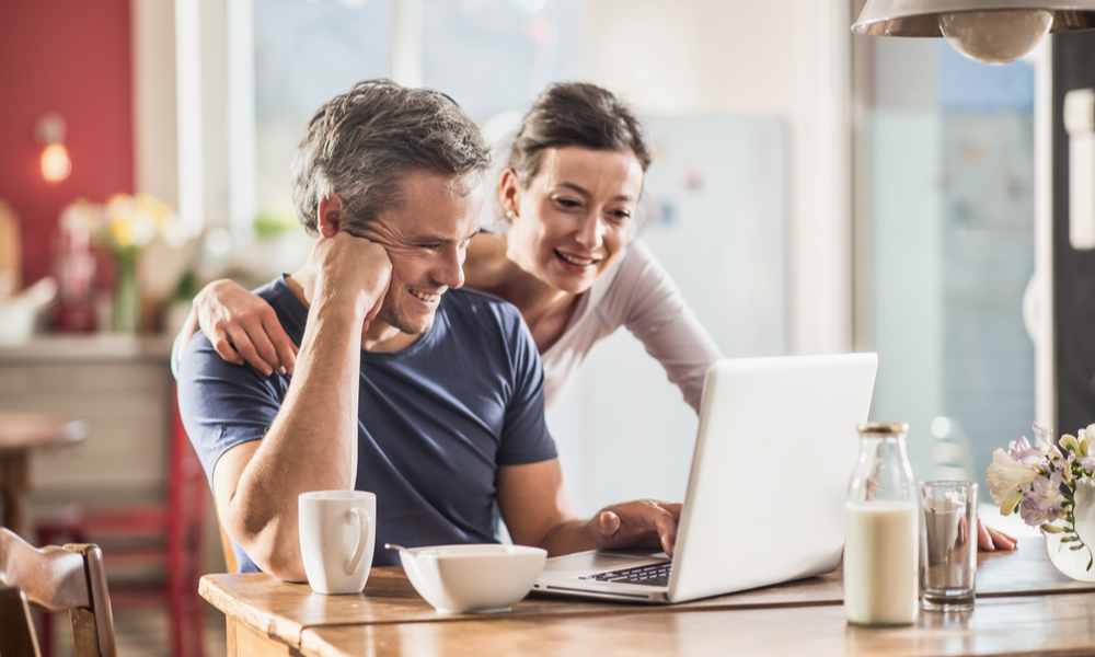 Nice thirty year couple using a laptop while having breakfast in the kitchen,