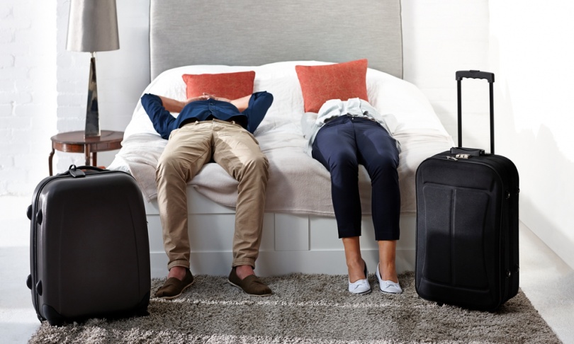 Simple Ways to Deal with Jet Lag on International Flights: Indoor shot of mature couple lying on bed with luggage