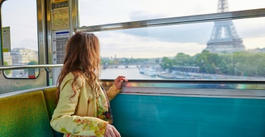 best day trips from paris: Beautiful young woman travelling in a train of Parisian underground and looking through the window at the Eiffel tower